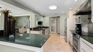 Een moderne keuken met granieten aanrechtbladen, roestvrijstalen apparatuur en inbouwspots.