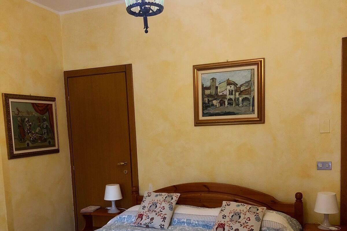 Une chambre à coucher avec un lit en bois, un lustre, une porte et deux tableaux encadrés accrochés au mur.
