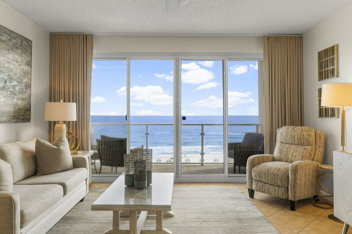 Een moderne woonkamer met een grote schuifpui naar een balkon met uitzicht op de oceaan.
