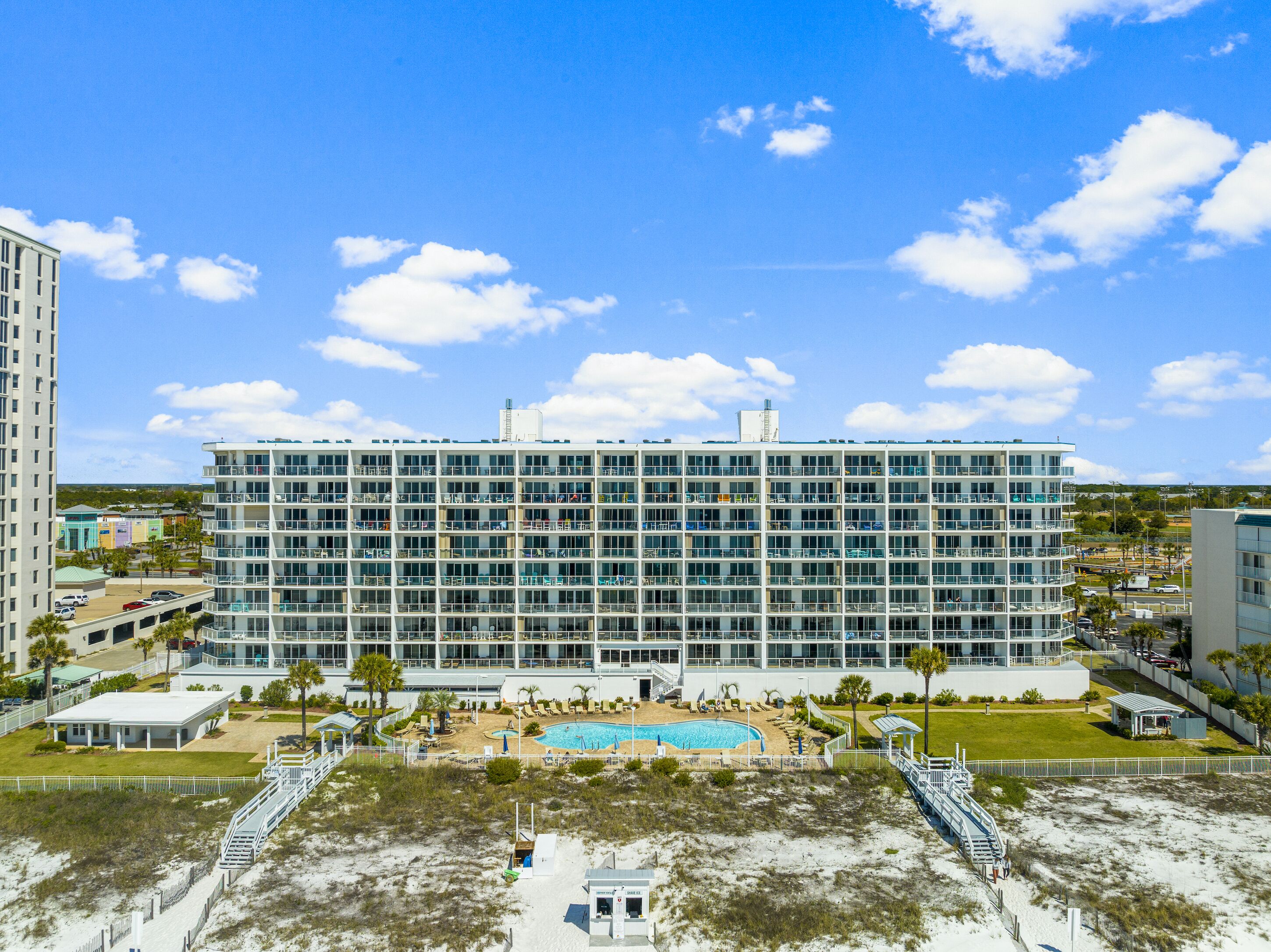 A multi-story hotel with a swimming pool and beach access.