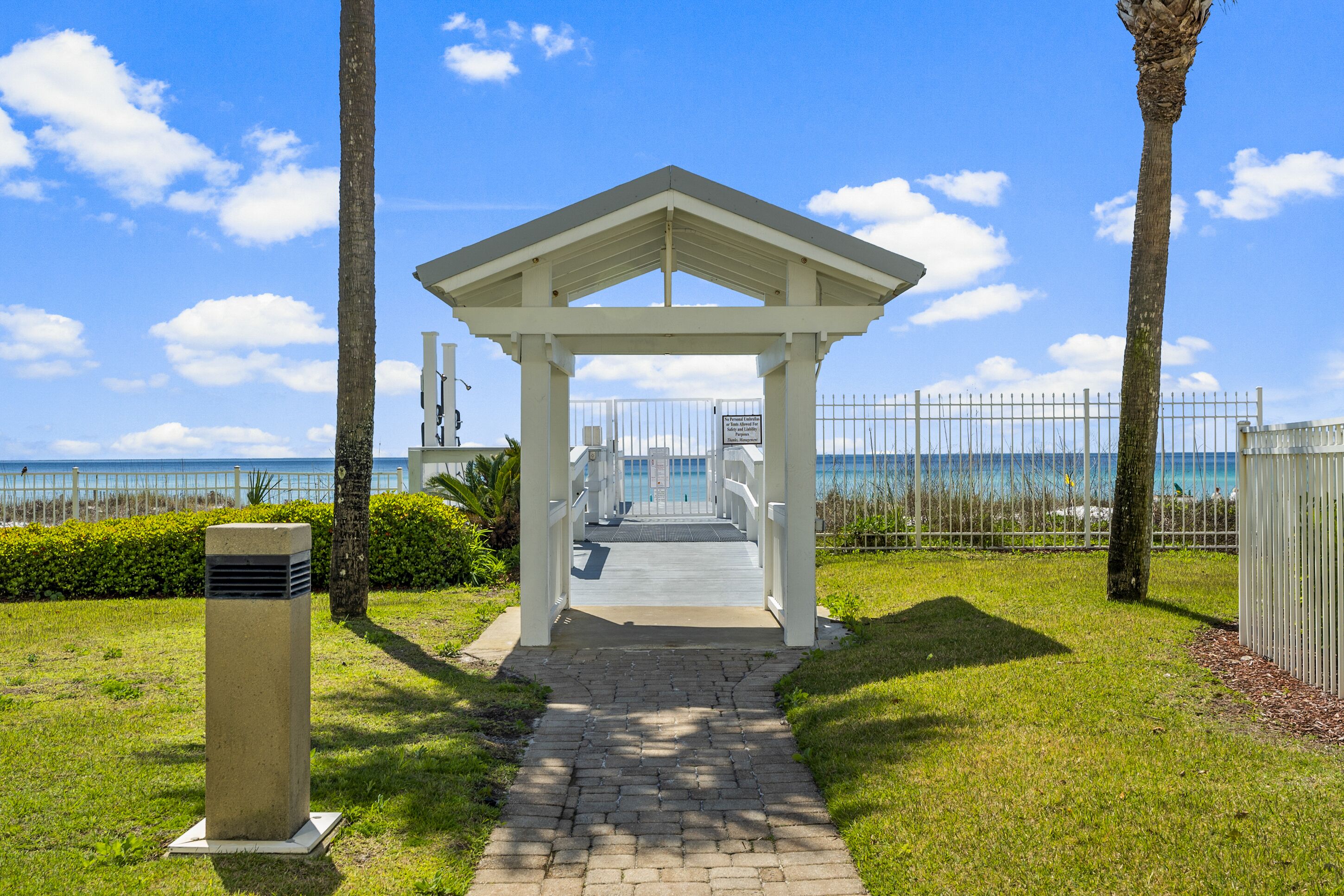 A covered walkway leading to a beach area with a clear view of the ocean.