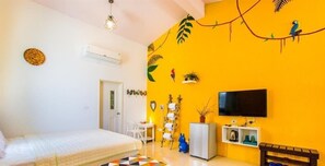 A room with a bed, a TV, a small table, and a shelf with decorative items. - Kenting Trail Villa (Hengchun)