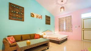 A room with a bed, a sofa, a small table, and a ceiling light. - Kenting Trail Villa (Hengchun)