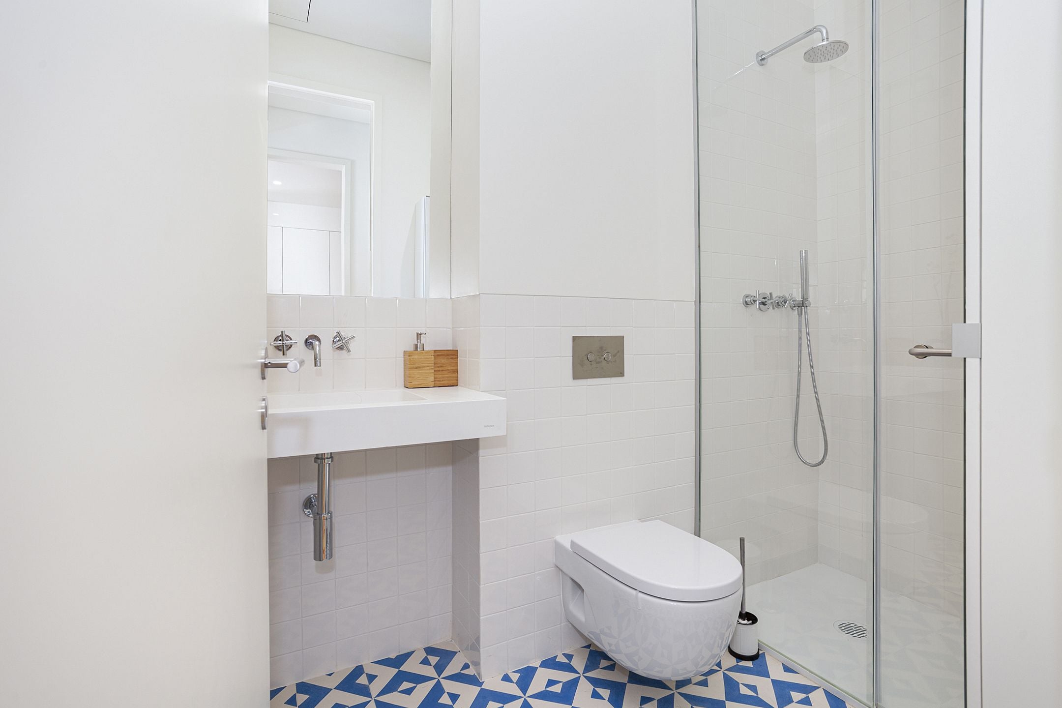 A modern bathroom with a white sink, toilet, and glass shower enclosure.