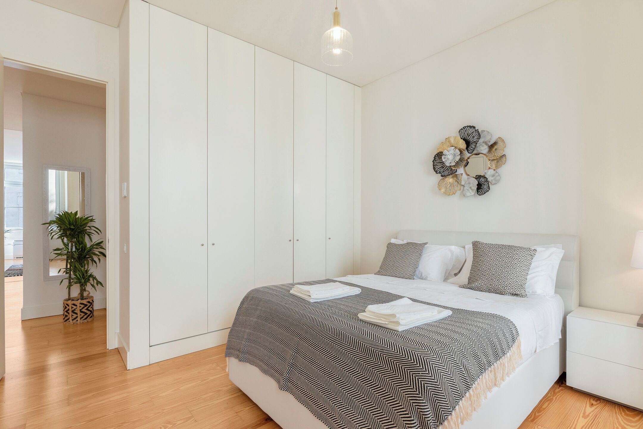 A bedroom with a bed, white wardrobe, and a wall decoration.
