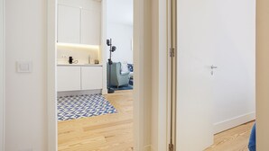 A modern kitchen with white cabinets, a coffee machine, and a blue and white patterned rug. - Gonzalo's Guest Apartments - Luxury Baixa (Lisbon)