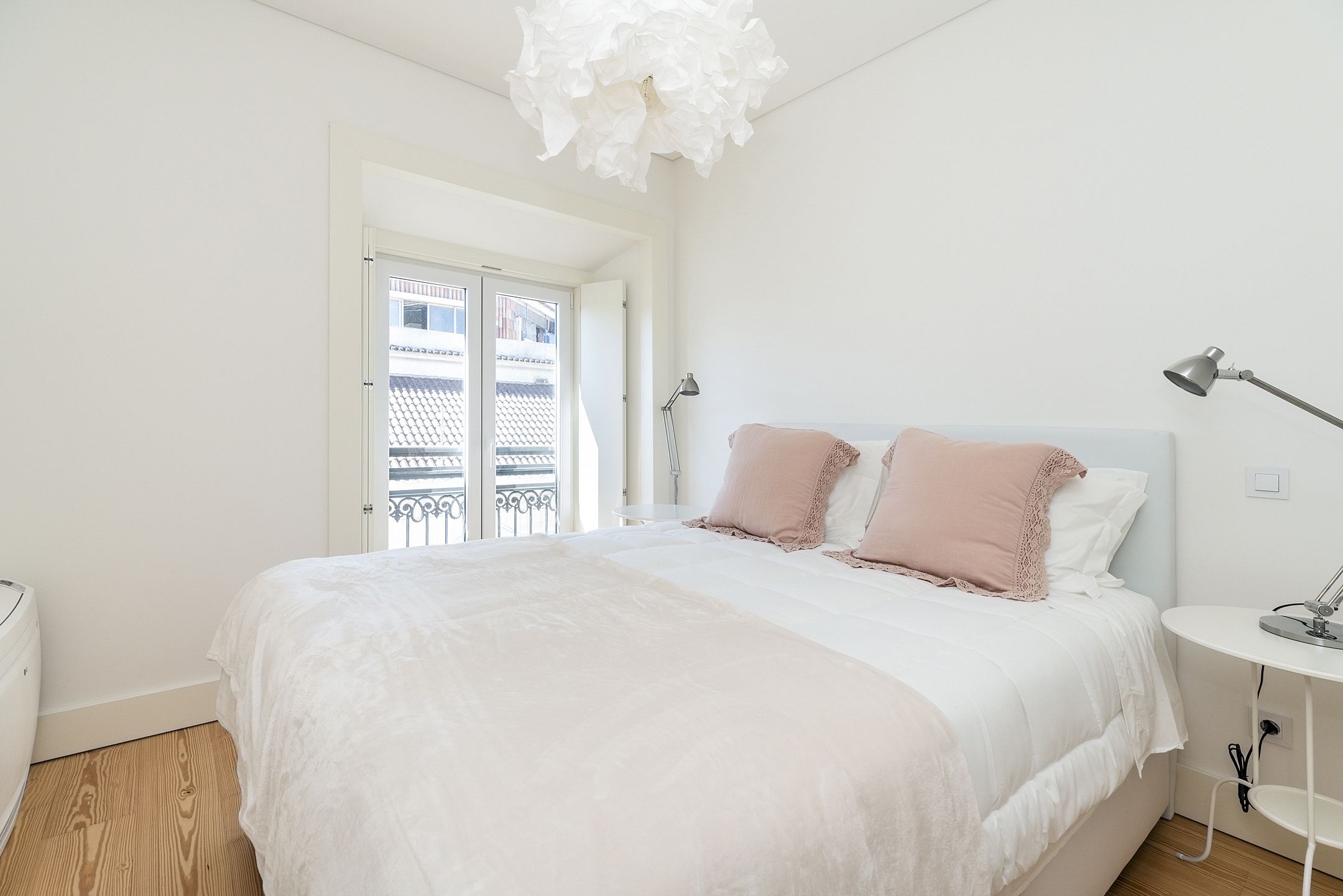 Ein Schlafzimmer mit einem großen Bett, einem Nachttisch, einer Lampe und Balkonblick.