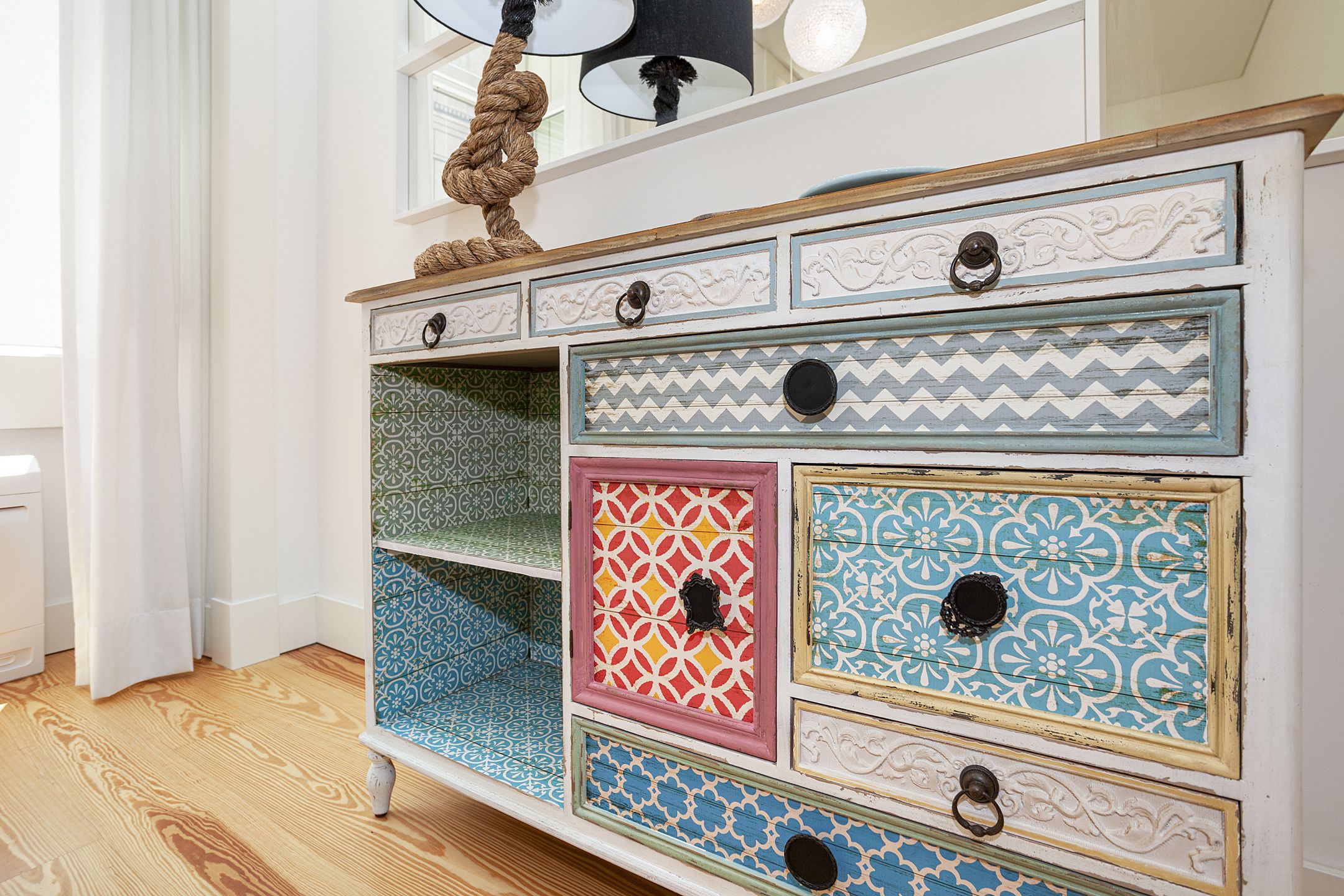 A white dresser with multiple drawers, each featuring different patterns and designs.