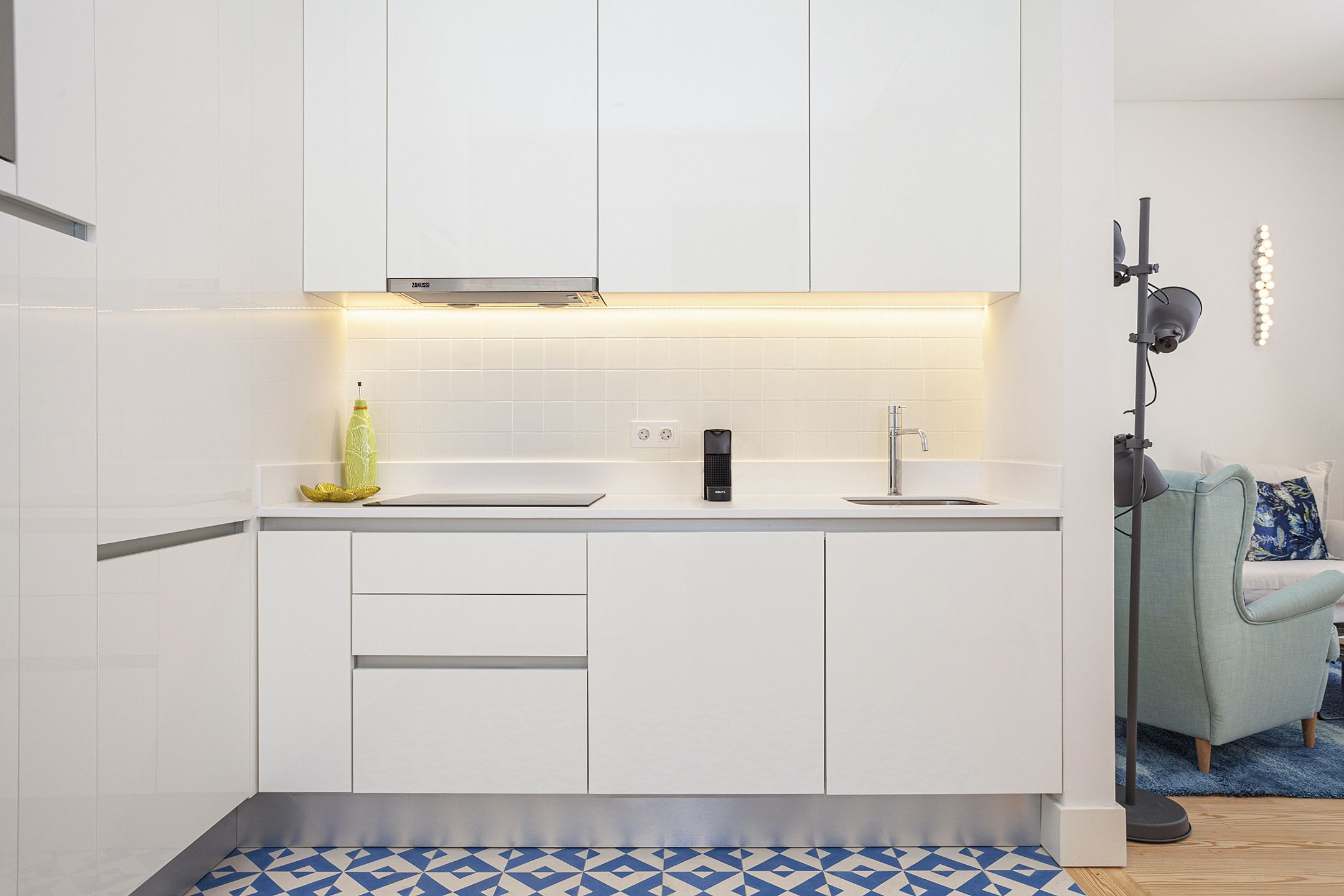A modern kitchen with white cabinets, a double sink, and a built-in range hood.