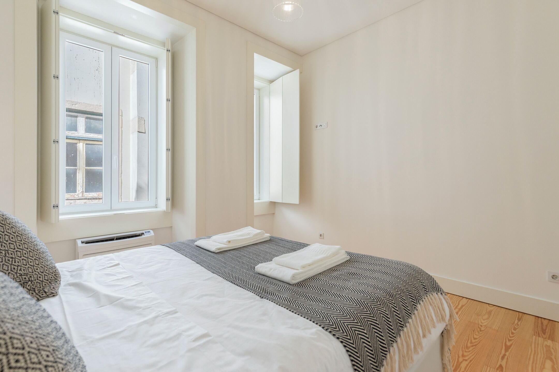 A bedroom with a bed, a window, a mirror, and a radiator.