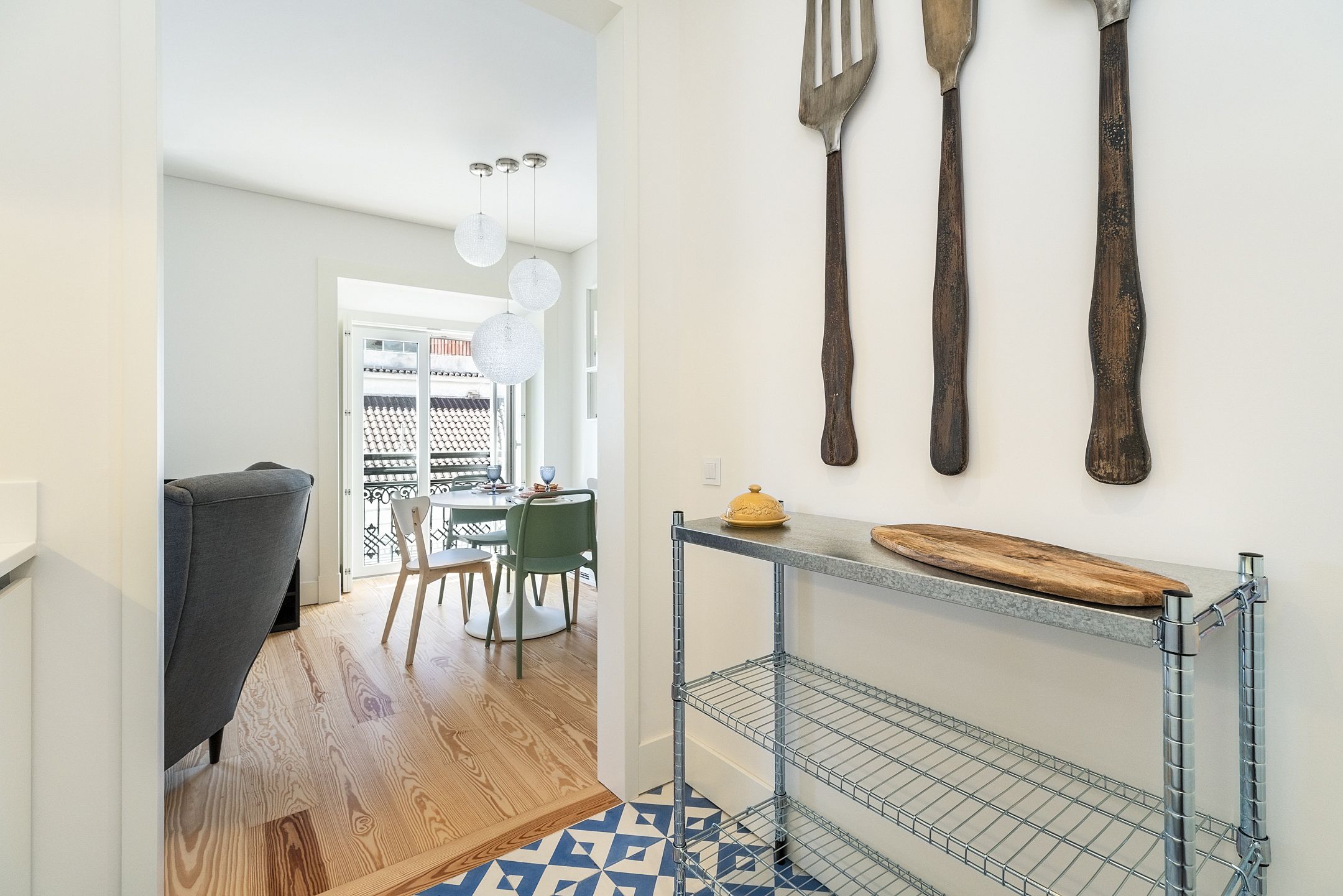 Une cuisine moderne avec un étagère en métal, une planche à découper en bois et des ustensiles suspendus.