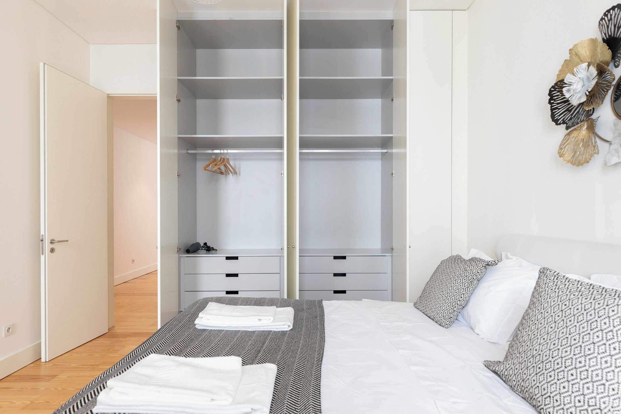 Quarto com cama, guarda-roupa e um objeto decorativo na parede.