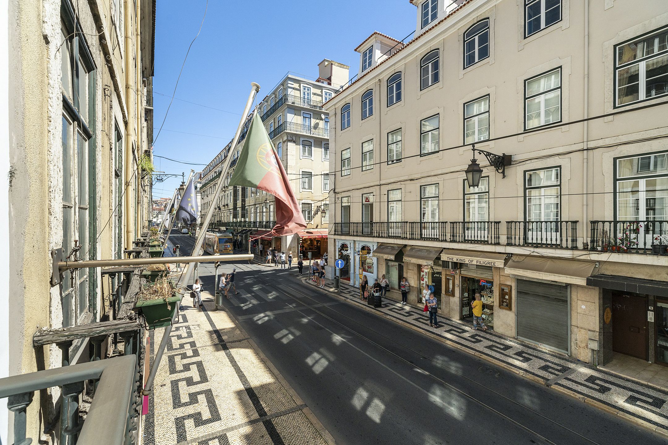 A street view with buildings, a tram, and pedestrians.