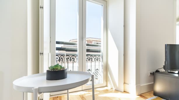 A balcony with a potted plant, a white table, and a television on a stand. - Gonzalo's Guest Apartments - Luxury Baixa (Lisbon)