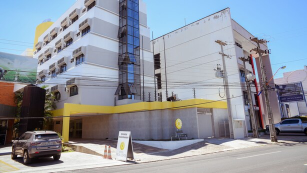 Un hôtel moderne à la façade jaune et blanche, doté de nombreux balcons et d’un espace de stationnement.