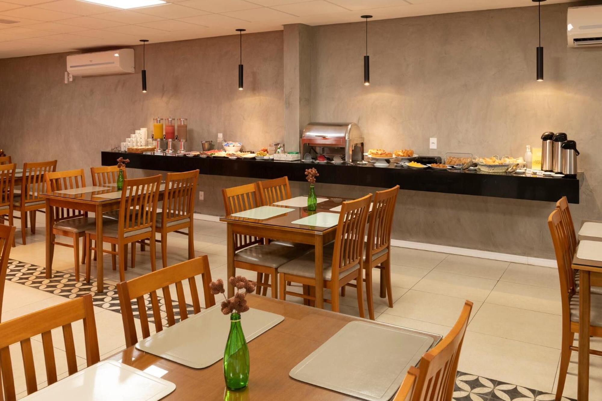 A dining area with wooden tables and chairs, a buffet counter with various food items, and hanging pendant lights.