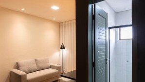 Une chambre moderne avec un canapé, une lampe sur pied et une cabine de douche en verre.