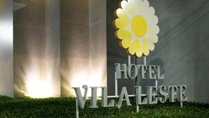 Une enseigne d’hôtel avec un soleil stylisé et l’inscription « HÔTEL VILA LESTE ».