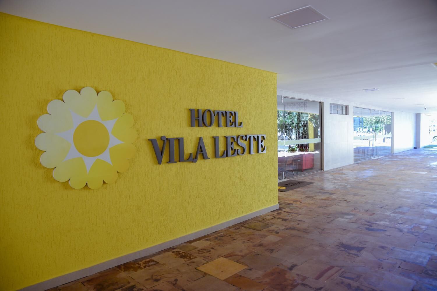 Una pared amarilla con un logo de sol y el texto "HOTEL VILA LESTE".