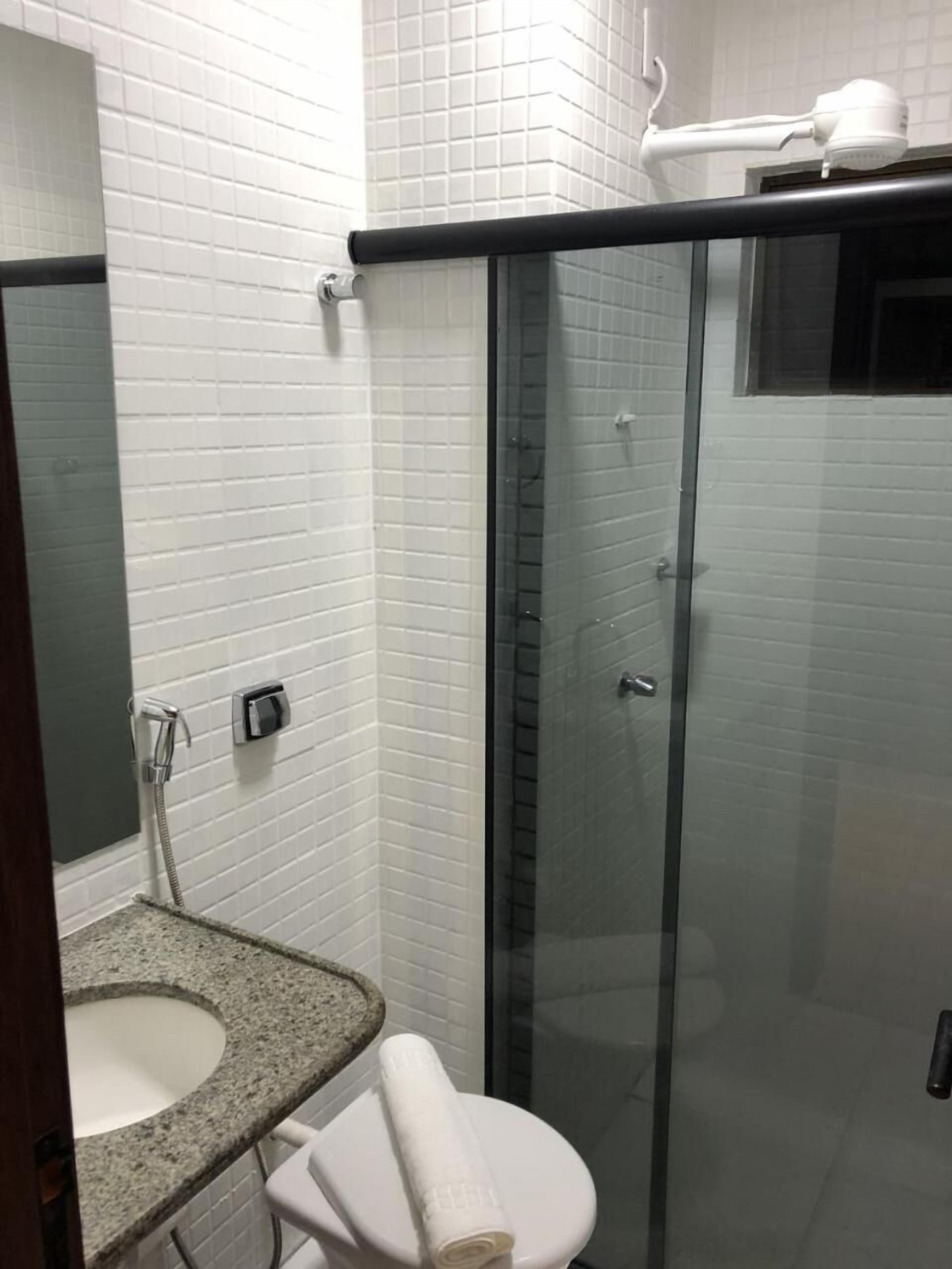 Een badkamer met een douche met glazen wand, een wastafel en een toilet.