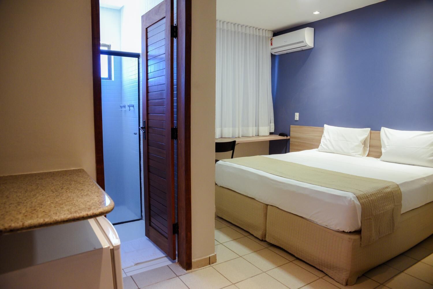 Una habitación de hotel con cama, escritorio y baño.