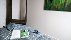 Un dormitorio con una cama, un cabecero de madera con cuatro postes, un libro y un cuadro abstracto verde en la pared.