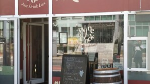 A storefront with a sign reading "Wine o' Clock" and "Art Vinot".