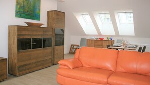 Una sala moderna con un mueble de madera, un sofá de cuero y un comedor con mesa y sillas.