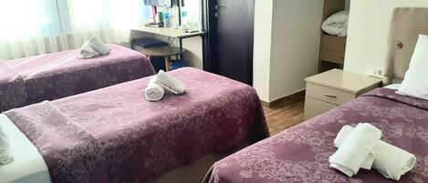 A hotel room with two beds, a desk, a chair, a wardrobe, and a mirror.