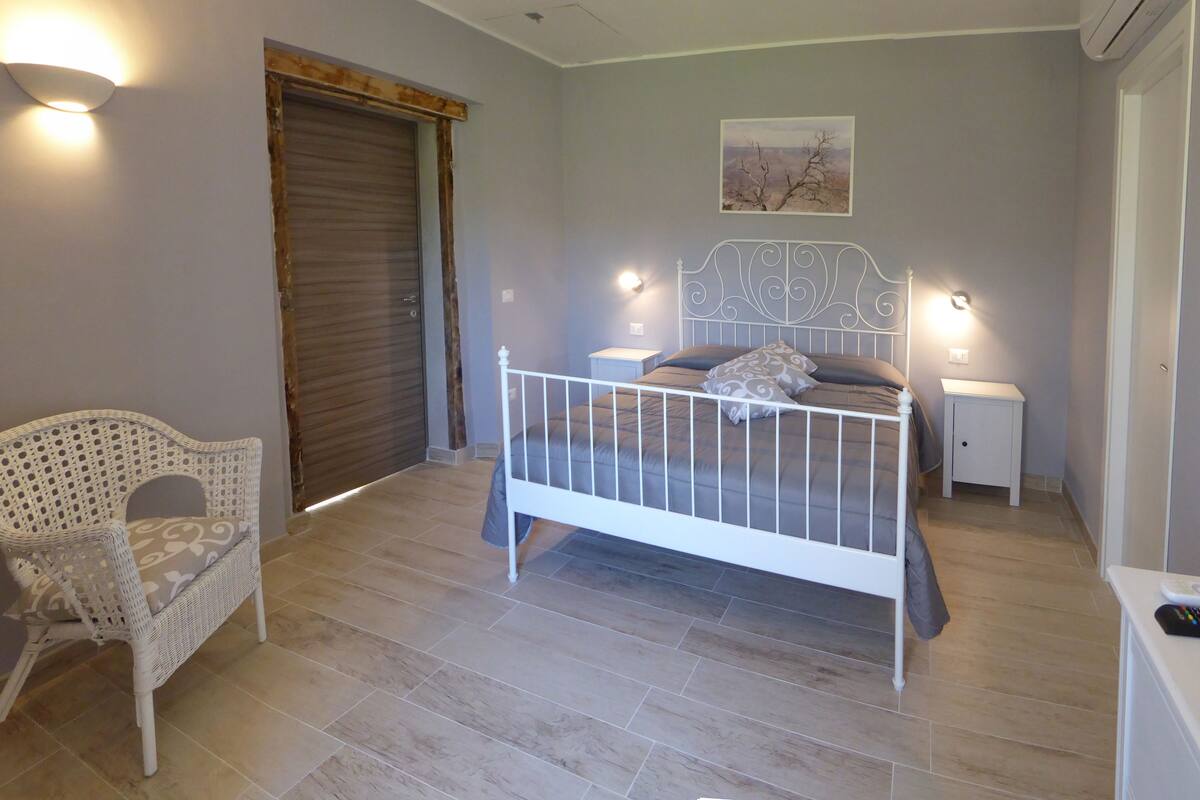 Une chambre à coucher comprenant un lit, une chaise, une table de chevet et un luminaire fixé au mur.