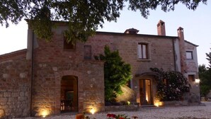 A stone building with a gravel driveway and a potted plant in the foreground. - Pietre di Fiume (San Giorgio del Sannio)