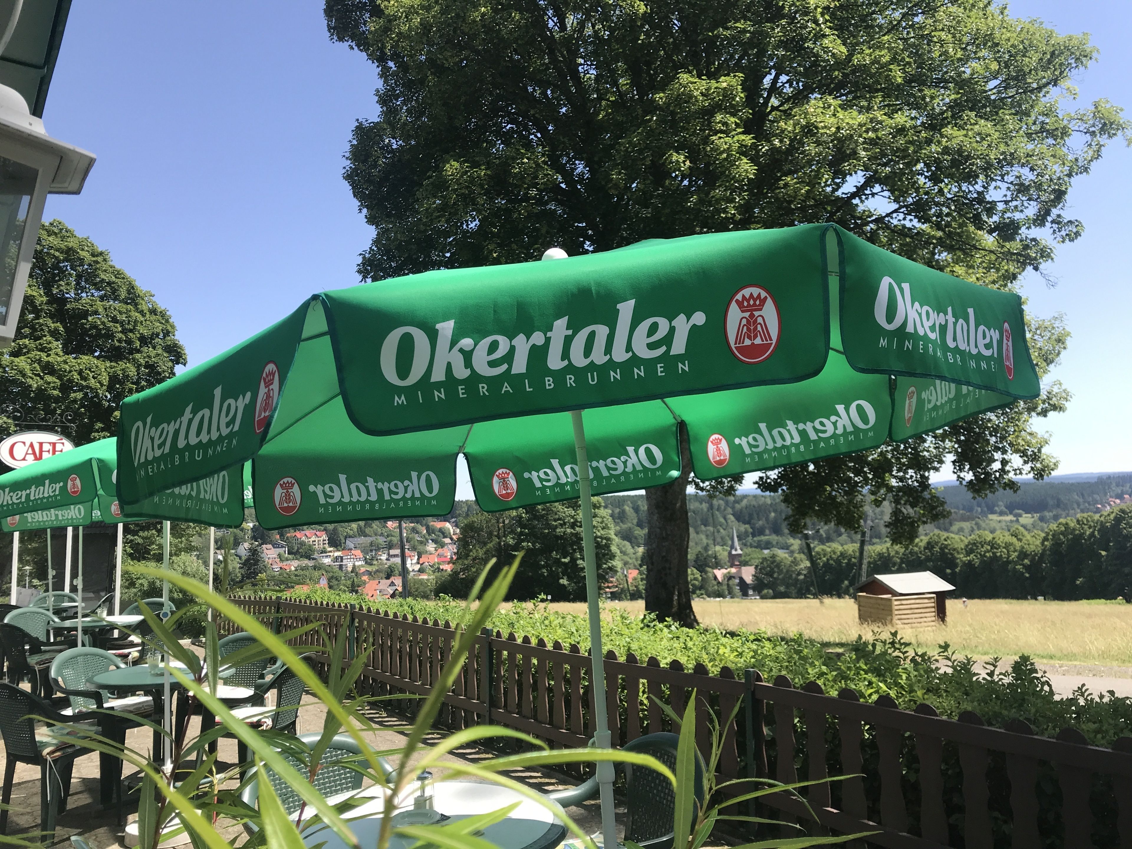 Buiten zitplaatsen met groene parasols, waarop 