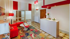 A modern living room with a red sofa, a coffee table, and a patterned rug. - Hotel & Café PANORAMA (Braunlage)
