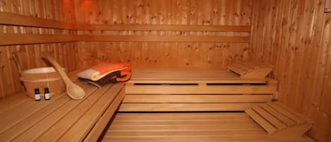 Una sauna de madera con bancos, una cuchara de madera y dos botellas de aceites esenciales.