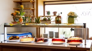 A buffet counter with various desserts and a window with plants in the background. - Hotel & Café PANORAMA (Braunlage)