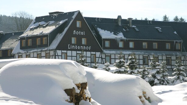 Un edificio tradicional con un cartel que dice "Hotel Lindenhof" en un paisaje nevado.