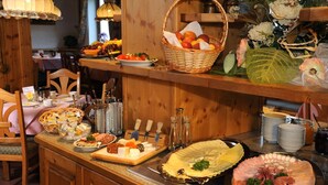 Montaje de bufé con diversos alimentos, como quesos, carnes y frutas, dispuestas sobre mesas de madera.
