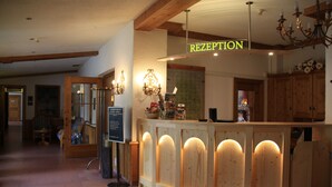 Un área de recepción con un mostrador de madera, un cartel que dice "RECEPTION" y un candelabro.