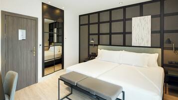 Una camera d'albergo moderna con un letto grande, una panca, una scrivania e uno specchio.