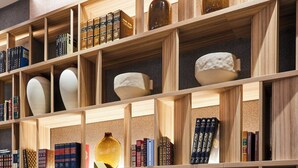 Un salon moderne avec une cheminée, un fauteuil bleu et une bibliothèque remplie de livres et d’objets décoratifs.