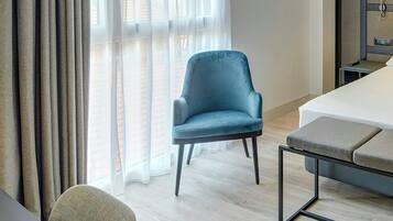 Habitación de hotel con cama, una silla, una mesita y ventana con cortinas.