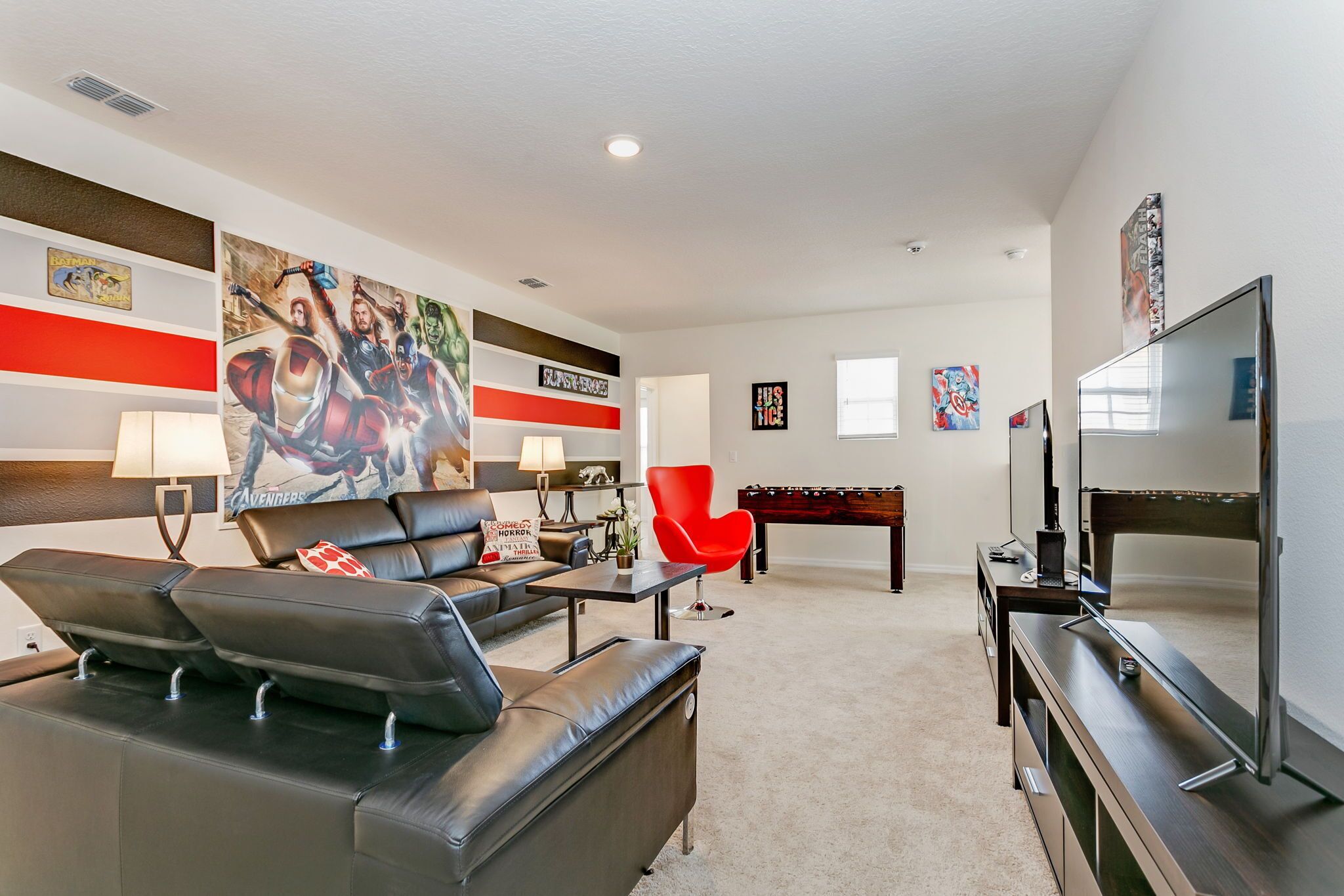 A living room with a sofa, red chair, and a foosball table.