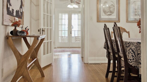 Un pasillo con piso de madera que conduce a un comedor con una mesa y sillas.