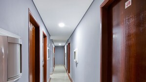 Un largo y estrecho pasillo con puertas a ambos lados, suelo de baldosas y una lámpara en el techo.