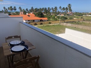A balcony with a table set for two, overlooking a residential area with palm trees and houses.