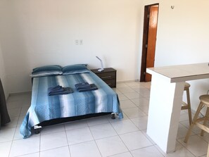 A bedroom with a bed, a bedside table, a desk, and a chair.