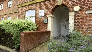 A red brick building with a sign indicating no unauthorized parking.