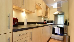A modern kitchen with wooden cabinets, a stainless steel range hood, a Bosch oven, and a red coffee maker.