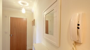 A hallway with a wooden door, a white wall-mounted telephone, and a mirror.