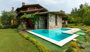 Una casa de piedra con piscina, rodeada por un jardín cuidado.
